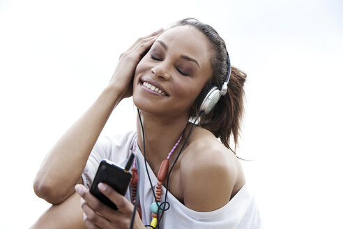 Deutschland, Junge Frau hört Musik mit Kopfhörern, lächelnd - GDF000087