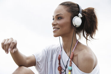 Deutschland, Junge Frau hört Musik mit Kopfhörern, lächelnd - GDF000099
