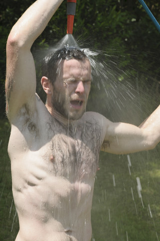 Deutschland, Baden Württemberg, Junger Mann duscht im Garten, lizenzfreies Stockfoto