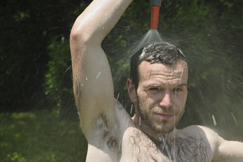 Deutschland, Baden Württemberg, Porträt eines jungen Mannes beim Duschen im Garten - LAF000083