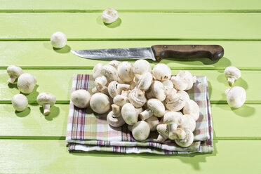 Mushrooms with kitchen knife on wooden table, close up - MAEF006856