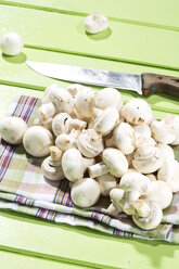 Mushrooms with kitchen knife on wooden table, close up - MAEF006855