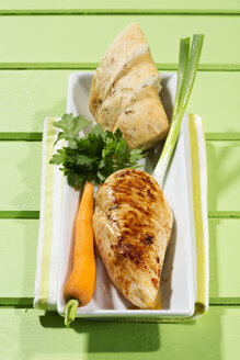 Hähnchenfilet mit Karotten, Frühlingszwiebeln und Brot auf einem Teller, Nahaufnahme - MAEF006848