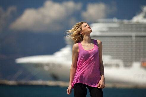 Griechenland, Junge Frau posiert vor einem Kreuzfahrtschiff - AJF000014