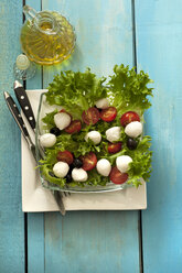 Plate of salad with oil bottle on wooden table, close up - OD000140