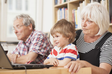Deutschland, Berlin, Großeltern und Enkel mit Laptop, lächelnd - ZMF000001