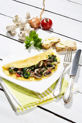 Omelett mit Pilzen auf Holztisch - MAEF006894