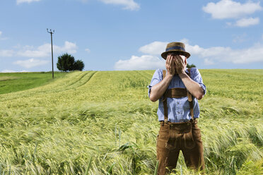 Deutschland, Bayern, Landwirt bedeckt sein Gesicht auf dem Feld - MAEF006902