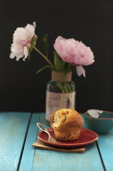 Süßer Muffin auf Teller und Pfingstrosenblüten im Hintergrund - OD000171
