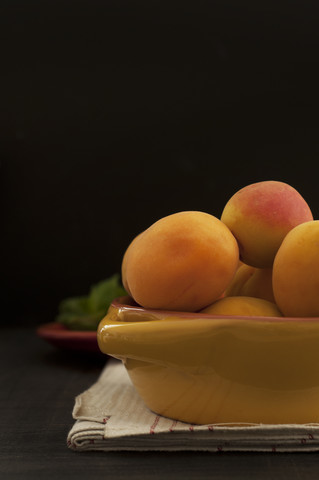 Schale mit Aprikosen mit Serviette auf Holztisch, Nahaufnahme, lizenzfreies Stockfoto