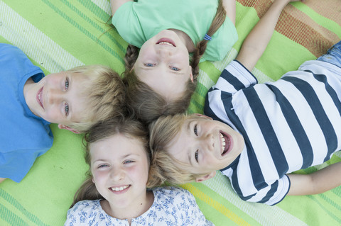 Germany, Bavaria, four smiling children lying on a blanket stock photo