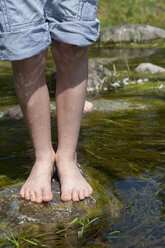 Germany, Bavaria, Munich, Boy standing on stone in creek - NH001387