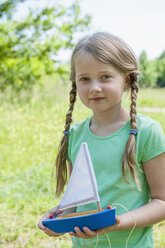 Germany, Bavaria, Munich, Portrait of girl holding boat, smiling - NH001365