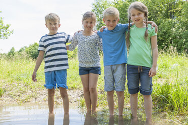 Deutschland, Bayern, München, Freunde stehen im Wasser, lächelnd - NH001405