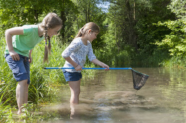 Germany, Bavaria, Munich, Girls with fishing net in lake - NH001408
