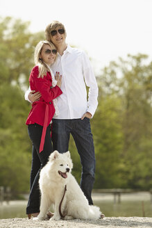 Germany, Young couple standing with dog, smiling - DSCF000087