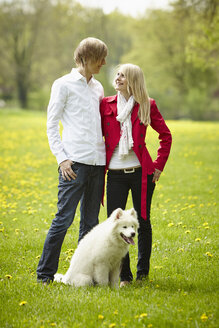 Germany, Young couple looking at each other with dog, smiling - DSCF000088