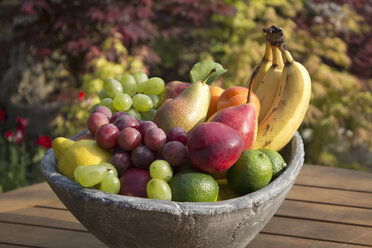 Germany, Rhineland Palatinate, Bowl of fruits on wooden table, close up - CSF019726