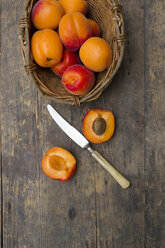 Korb mit Aprikosen und Messer auf Holztisch, Nahaufnahme - LVF000140