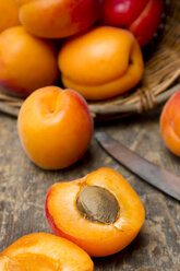 Basket of apricots with knife on wooden table, close up - LVF000139