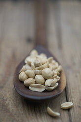 Peanuts in wooden spoon on wooden table, close up - ASF005005