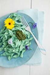 Hausgemachte blaugrüne Nudeln mit Basilikum, Pesto und essbaren Blüten auf dem Teller - ECF000239