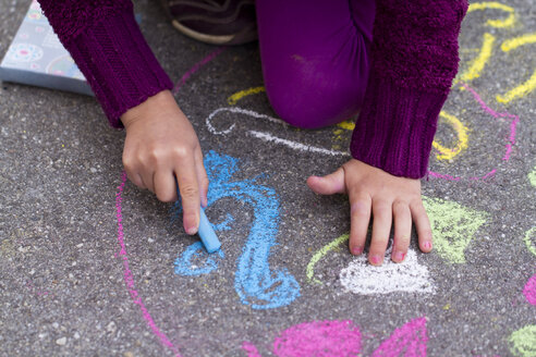 Deutschland, Mädchen malt mit Kreide auf der Straße - SARF000048
