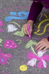 Deutschland, Mädchen malt mit Kreide auf der Straße - SARF000047