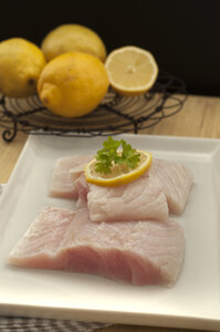 Roter Fisch in Schale mit Zitrone auf Holztisch, Nahaufnahme - OD000192