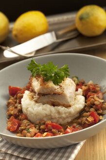 Bowl of red fish with lemon risotto and lentils on wooden table, close up - OD000189