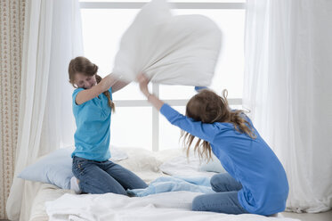 Germany, Bavaria, Girls pillow fighting on bed - CRF002436