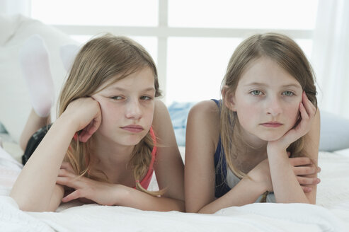 Germany, Bavaria, Sad girls lying on bed - CRF002448