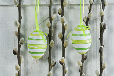 Easter eggs with willow catkin twigs hanging on wooden door, close up - ASF005028