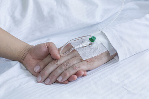 Germany, Freiburg, Woman holding hand of man in hospital, close up - DRF000022