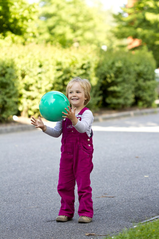 Deutschland, Kiel, Mädchen fängt grünen Ball, lächelnd, lizenzfreies Stockfoto