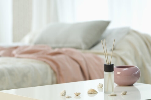 Aromatherapie und Räucherstäbchen auf einem Tisch mit einem Bett im Hintergrund - ASF005037
