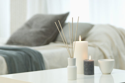 Aromatheraphy, candles and incense sticks on table with bed in background - ASF005039