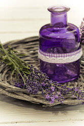 Lavender flowers with basket and bottle on wooden table, close up - SARF000054