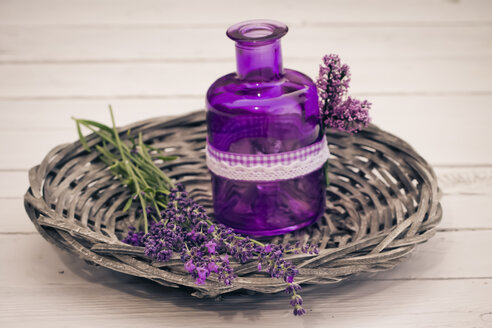 Lavendelblüten mit Korb und Flasche auf Holztisch, Nahaufnahme - SARF000060