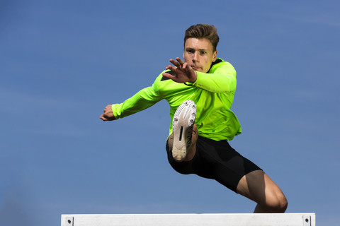 Deutschland, Mann Athlet springt Hürden auf der Bahn, lizenzfreies Stockfoto