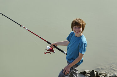 Young boy holding up fishing rod and fish stock photo