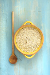 Bowl of pearl barley with wooden spoon on table, close up - OD000242