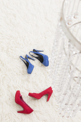 Rote und blaue High Heels liegen auf weißem Teppich, lizenzfreies Stockfoto