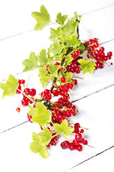 Red currants with shrubs on wooden table, close up - MAEF006939