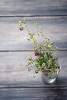 Deutschland, Baden Württemberg, Strauß Walderdbeeren im Glas auf Holztisch - SBDF000110