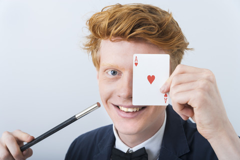 Porträt eines jungen Mannes, der die Magie der Karten zeigt, lächelnd, lizenzfreies Stockfoto