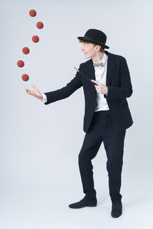 Young man showing magic with ball, smiling - TCF003485