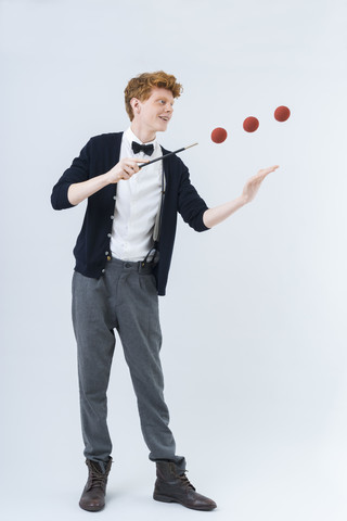 Junger Mann zeigt Magie mit Ball, lächelnd, lizenzfreies Stockfoto