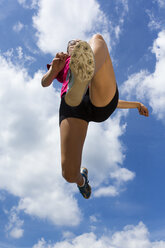 Germany, Young woman doing long jump in track - STSF000089