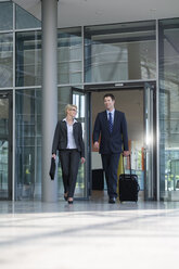 Germany, Hannover, Businessman and businesswoman walking with briefcase at terminal - KFF000084